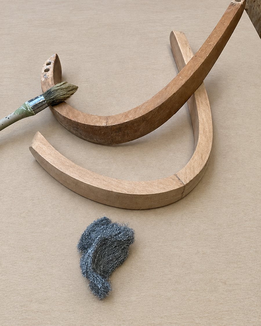 Bois cintrés d'un fauteuil, pinceau et laine d'acier posés sur l'établi